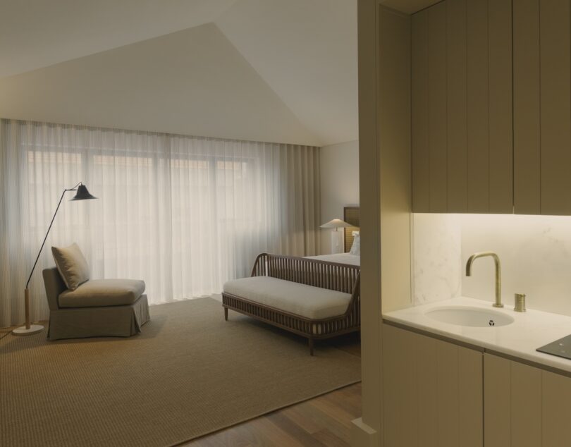 Suite featuring a comfortable lounge chair, daybed, and a small kitchenette, all designed in soothing neutral tones