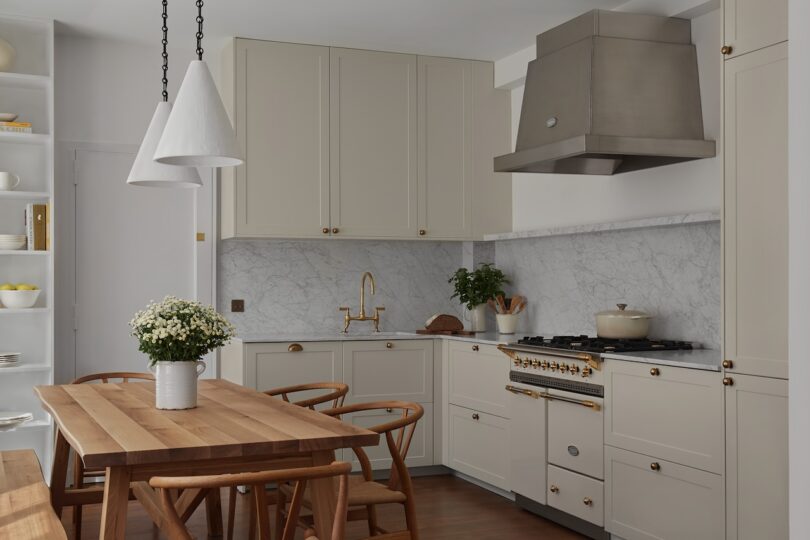 A wide view of the kitchen, highlighting a wooden dining set paired with elegant white cabinetry