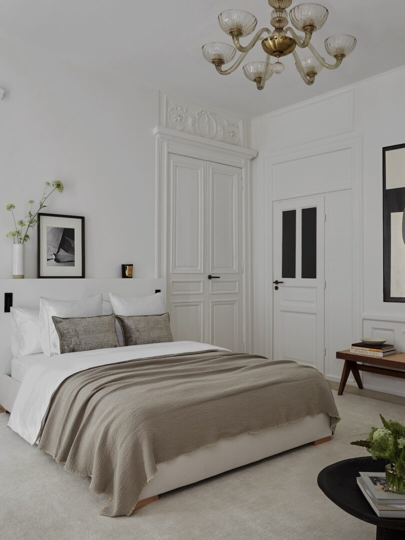 A serene bedroom with muted tones, a plush bed, and a vintage Venini chandelier